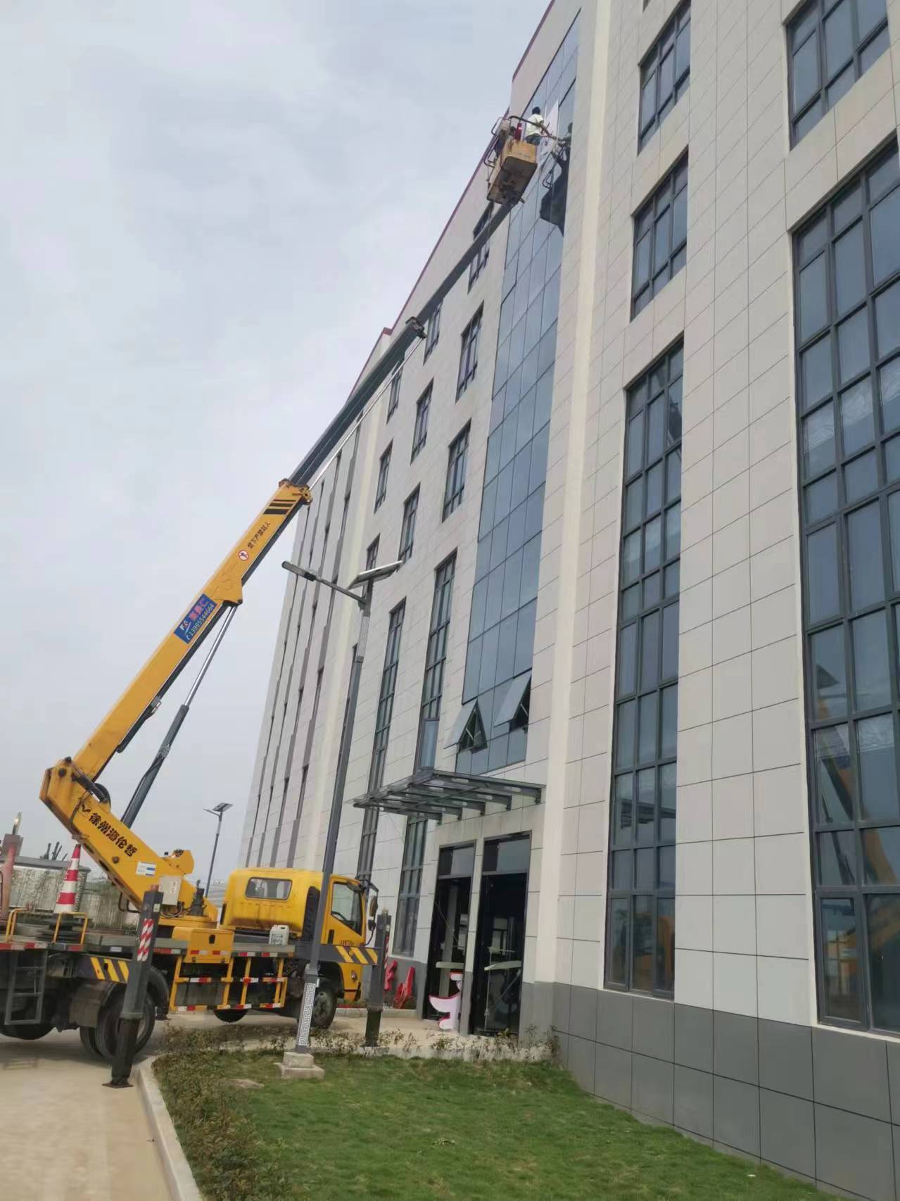 24米升降車(chē)高層樓外墻換玻璃施工現(xiàn)場(chǎng)